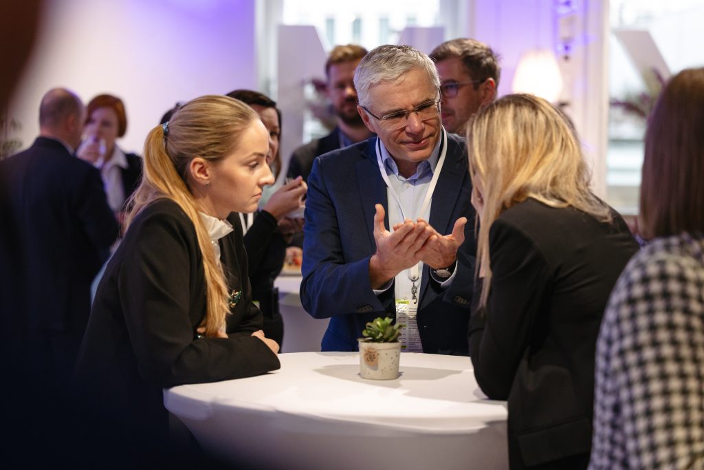 uczestnicy konferencji stojący przy stoliku koktajlowym