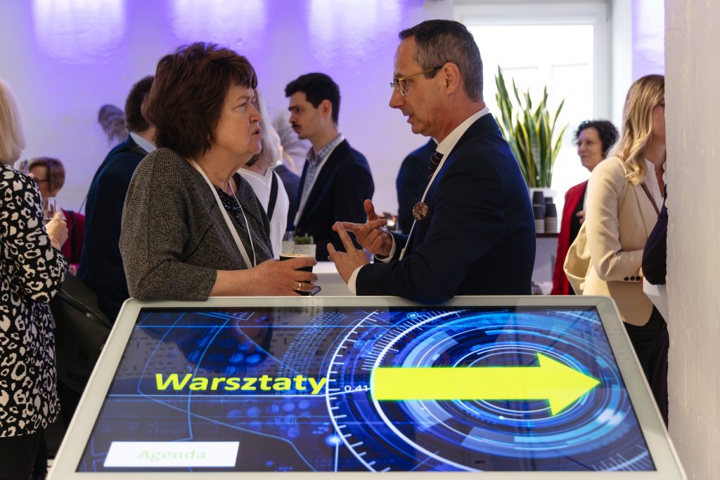 ekran warsztatów i stojący przy nim ludzie