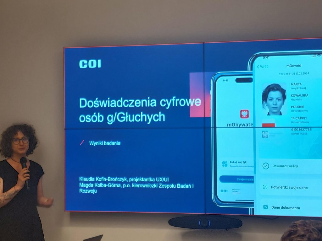 stojąca kobieta przy dużym ekranie