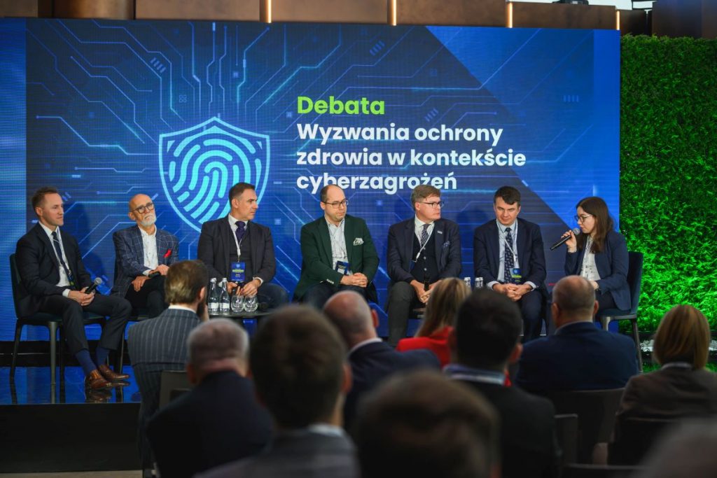 uczestnicy debaty siedzący na scenie